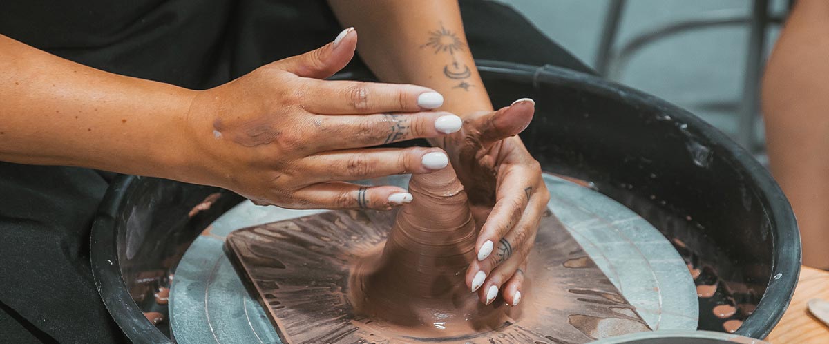 A closeup of a woman's hands molding clay.