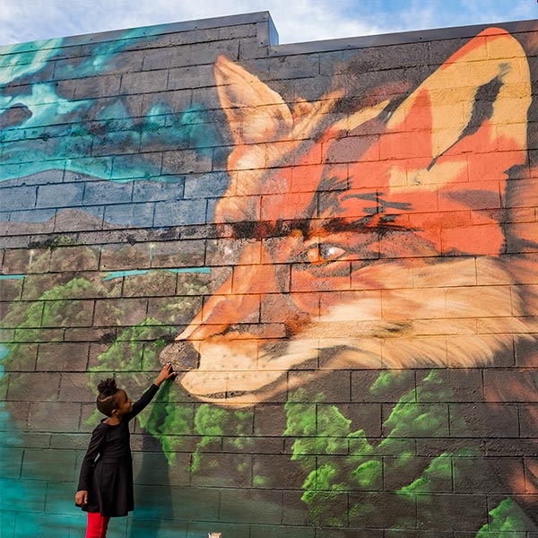A young girls looking at a mural of a fox.
