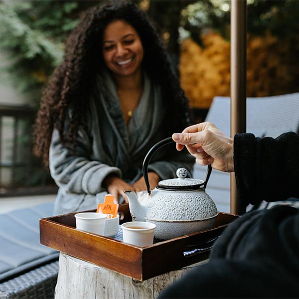 A woman in a robe being served tea.