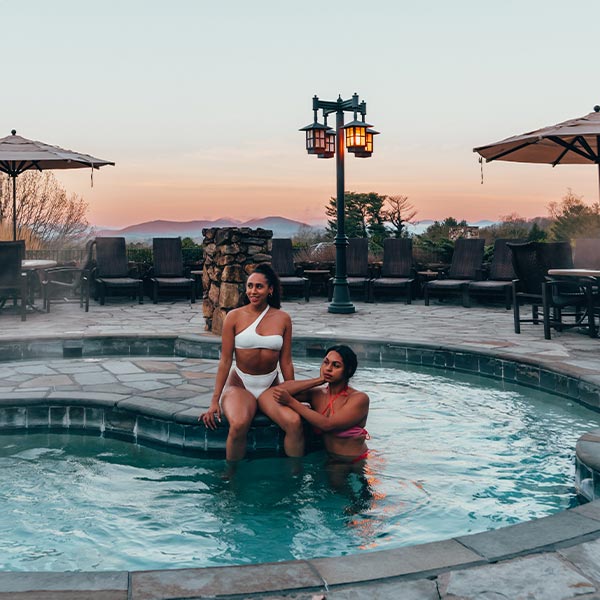 Two women sitting in a hot tub at dusk.