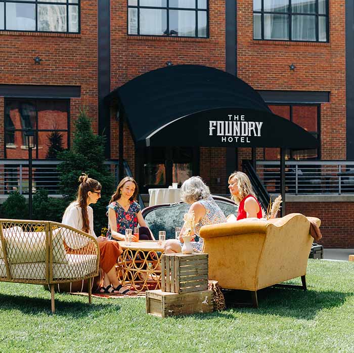 A group sitting around a table outside of the Foundry hotel.