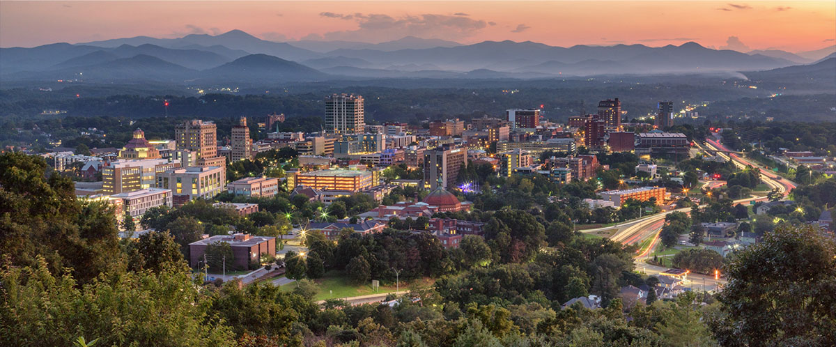 An aerial view of Asheville with mountains in the background.