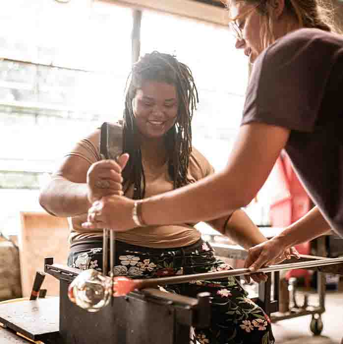 A woman learning how to blow glass.