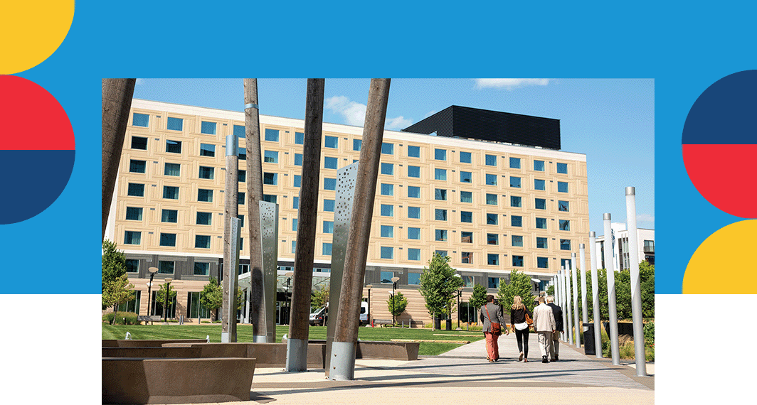 A group walking towards a building covered in windows used as a meeting space.