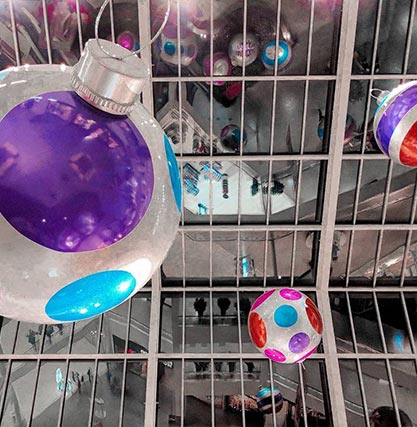 A photo of giant silver ornament decorations hanging from the ceiling.