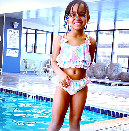 A photo of a young girl by a swimming pool.