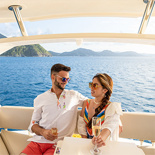 A couple sitting on a boat drinking champagne in the ocean.