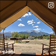 Cloud shadows on a mountain range on a sunny day from the view of an open tent, several miles away.