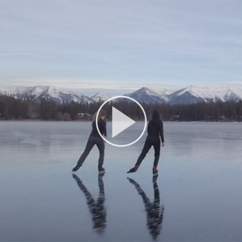 Two people ice skating on a frozen lake