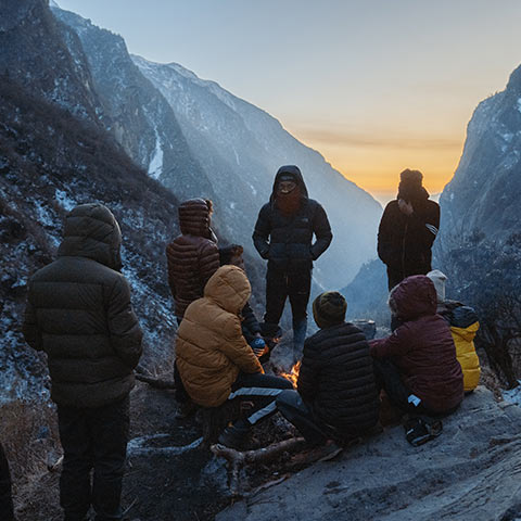 Group gathered around a campfire in the mountains.