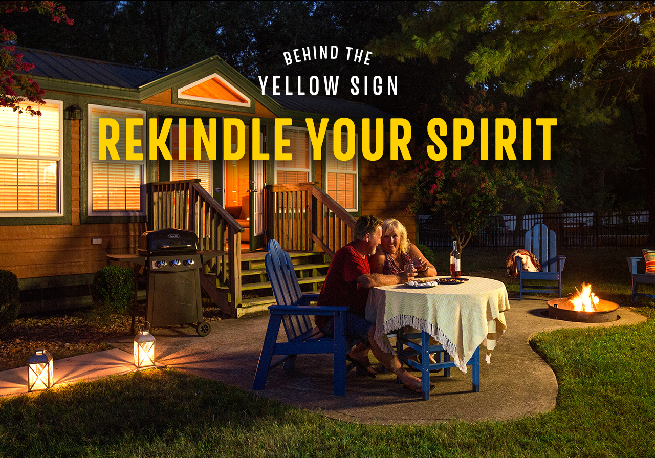 Behind the Yellow Sign Rekindle Your Spirit. A couple sitting outside a cabin eating dinner.