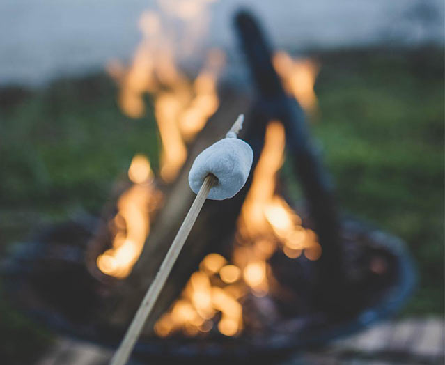Roasting a marshmallow over a camp fire.
