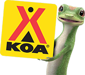 Why Choose Geico? Gecko holding a KOA sign.