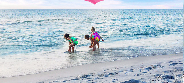 Picture of three kids playing in the ocean surf. 