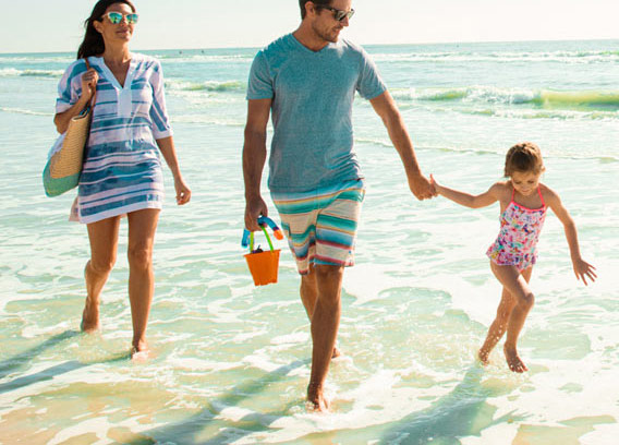 A family walking hand in hand on the beach.