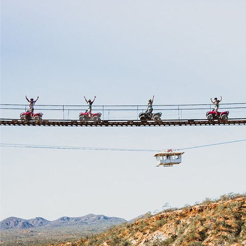 Quads going over a bridge with mountains in the distance.