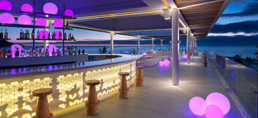 Image of the covered outdoor bar with its view of the ocean at night. 