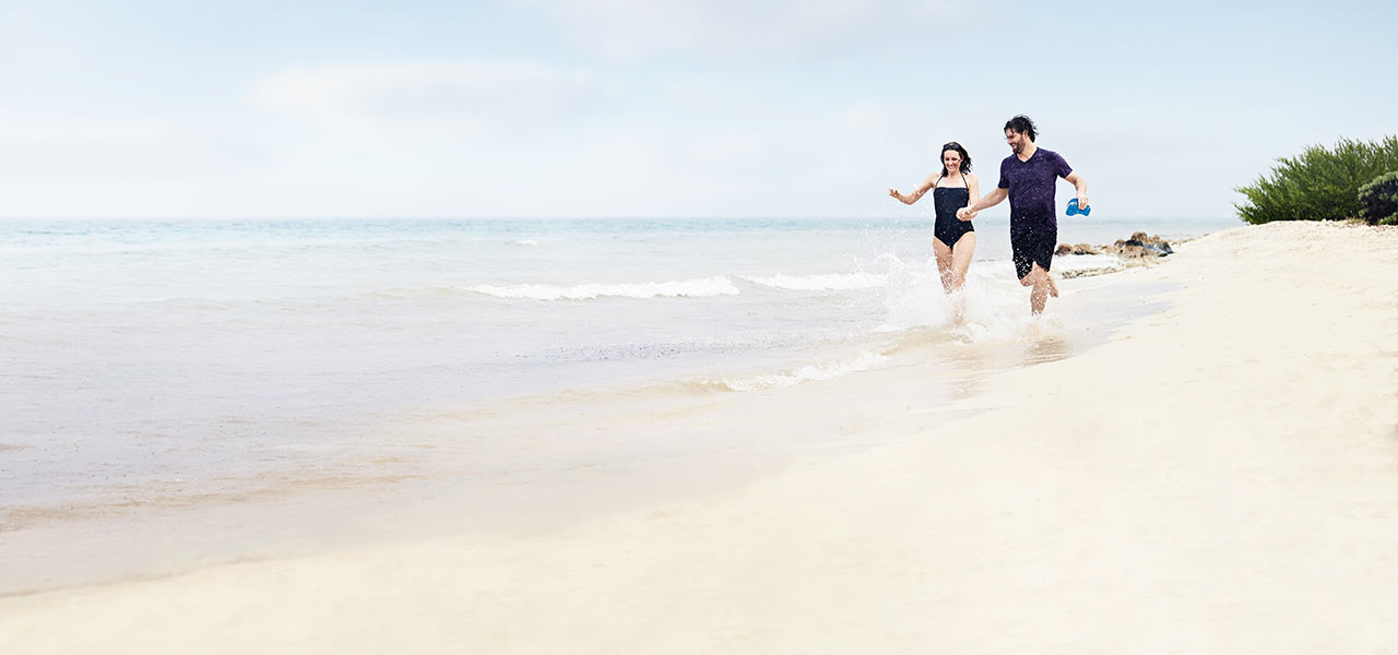 A couple runs on a white-sand beach