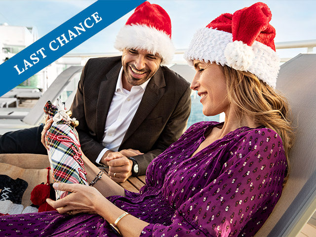 A man and woman lounging on board in Santa hats