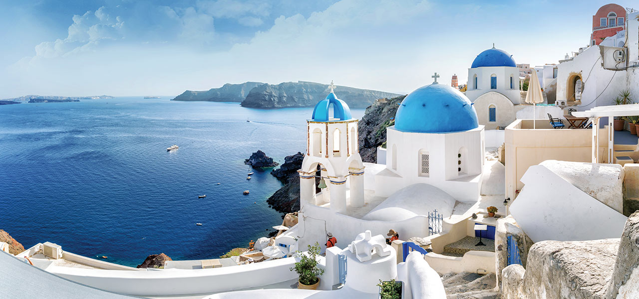 White buildings with blue roofs in Santorini, Greece. Click here to book.