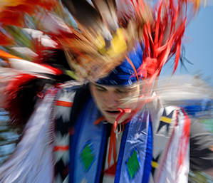 A Native American dancing with the traditional headdress
