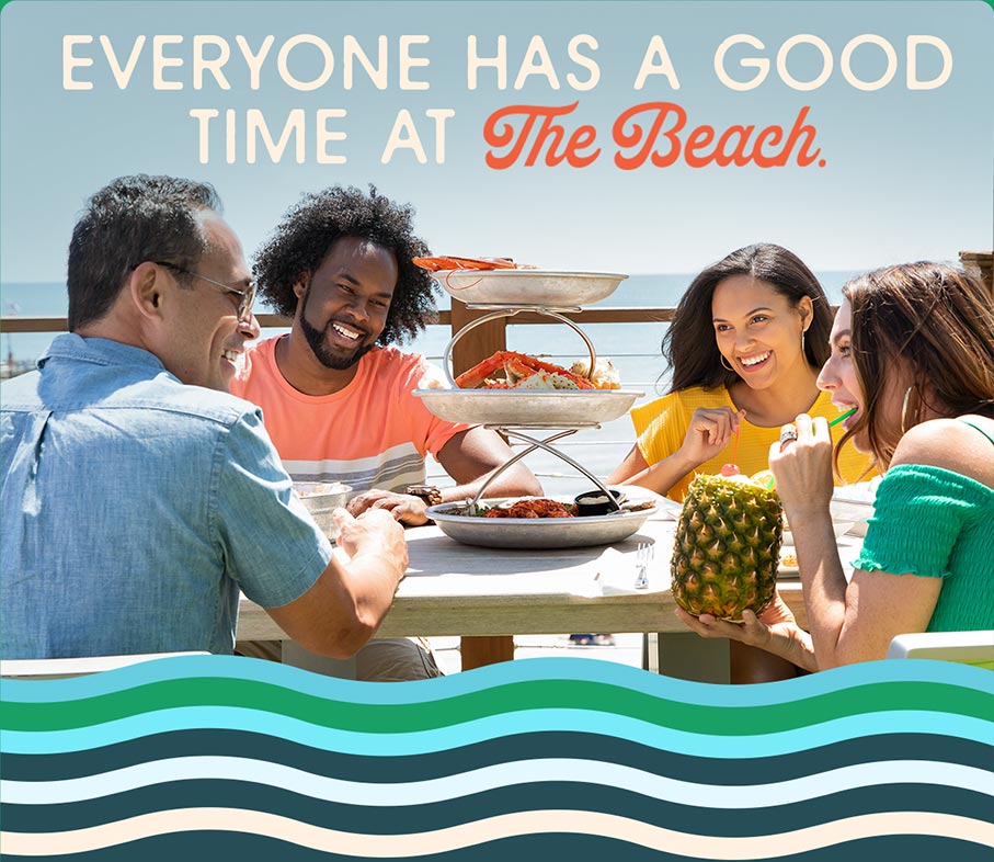 A photo of two couples enjoying a meal on  deck overlooking the water.  A headline reads: Everyone has a good time at the beach.