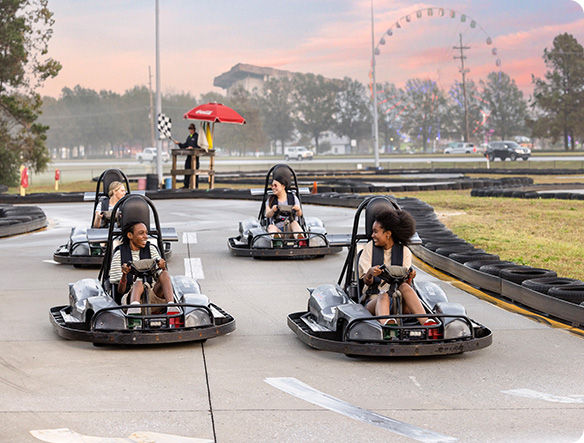 Four youth riding go karts and smiling.